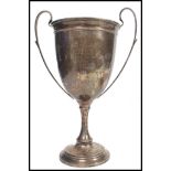 A hallmarked silver large trophy cup raised on a stepped circular base with scrolled twin handles to
