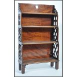 A 19th century Georgian solid mahogany ecclesiastical four tier waterfall bookcase having fretted