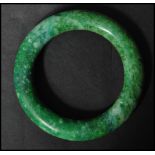An Oriental carved Chinese jade bangle of circular form. The bangle of deep green colour.