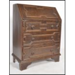 A 1920's Jacobean oak bureau desk raised on bracket legs with geometric panelled drawers under