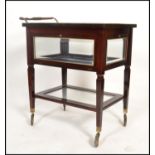 An unusual mid century mahogany and glass bijouterie display cabinet trolley. Raised on castors to