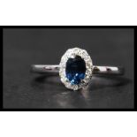 A hallmarked 18ct white gold sapphire and diamond ring having a central oval cut sapphire surrounded