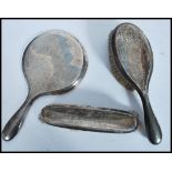 A silver hallmarked three piece brush and mirror set by Henry Matthews bearing Birmingham