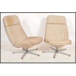 A pair of contemporary swivel lounge armchairs, raised on chrome supports surmounted by