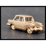 A hallmarked 9ct gold miniature model of a Triumph Herald with working wheels. Weighs 5 grams.