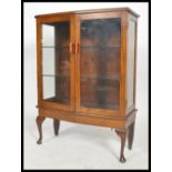 A 1930's Art Dec oak bookcase display cabinet having shaped cabriole legs with twin doors housing