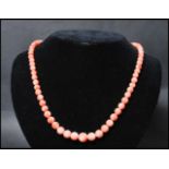 A vintage angel skin coral necklace. The necklace of graduating form each bead carved and strung set