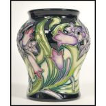 A Moorcroft ceramic vase tube lined decorated with flowers in the Isis pattern complete in