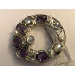 A silver moonstone, amethyst and pearl brooch pin of roundel form with entwined gemstone studded