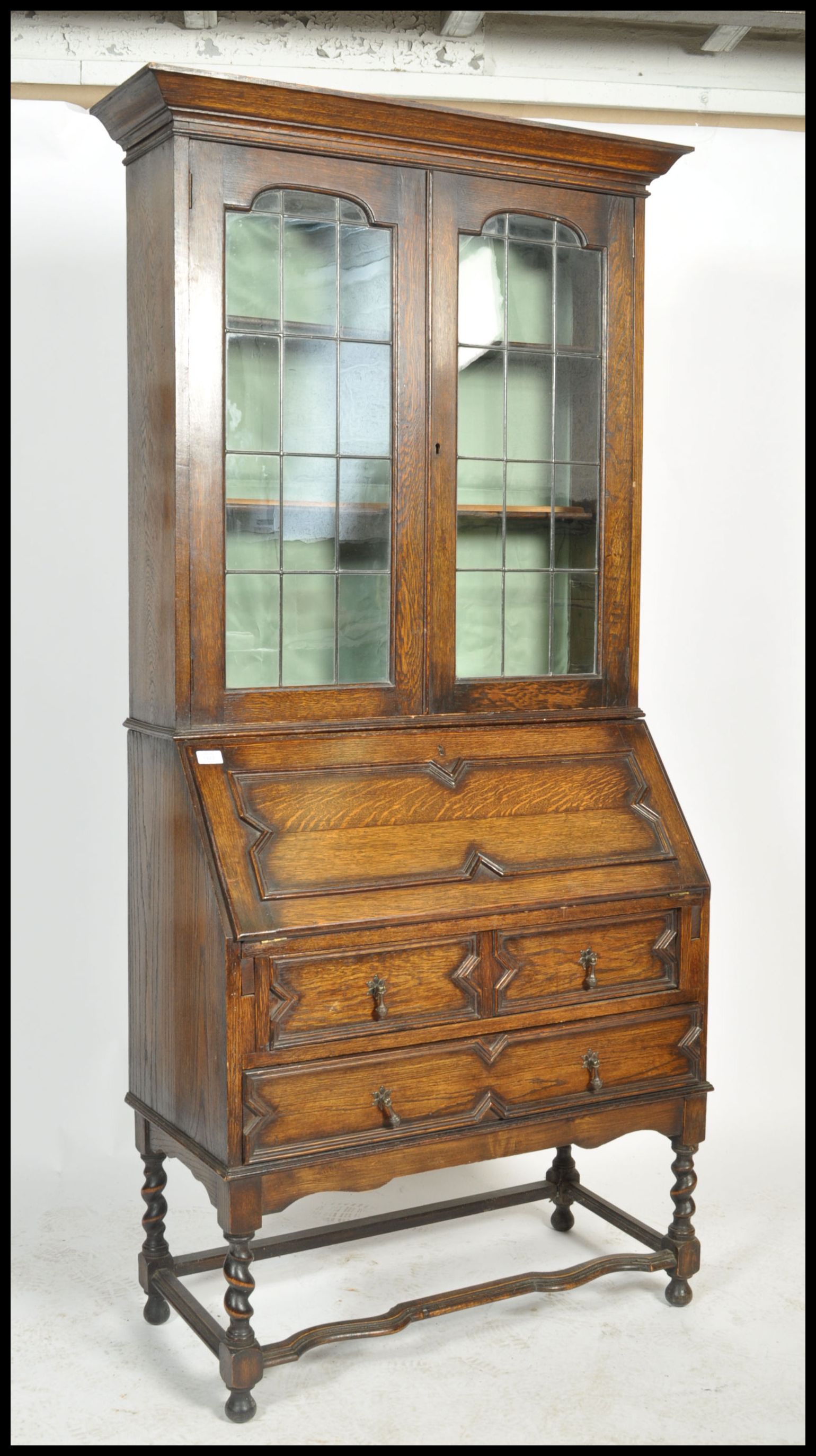 An early 20th century oak Jacobean revival bureau bookcase. Raised on barley twist supports with