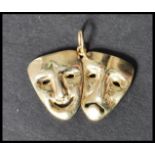 A 9ct gold pendant in the form of comedy and tragedy masks having circular bail hoop atop. Stamped