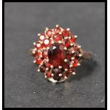 A hallmarked 9ct gold garnet stone cluster ring. The central stone adorned with two layers of garnet