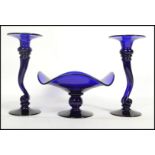 A group of three Bristol Blue glass items to include a pair of vases on circular bases with scrolled