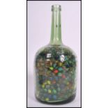 A large collection of vintage 20th century glass marbles contained within a large glass bottle