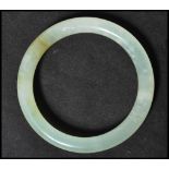 A Chinese jade bangle of circular form. The plain bangle having a light green colour.