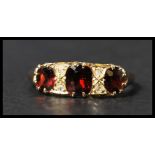 An early 20th century hallmarked 18ct gold garnet and diamond ring set with three oval cut garnets