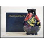 A Moorcroft ceramic vase tube lined decorated with flowers in the Anemone Blue pattern complete in