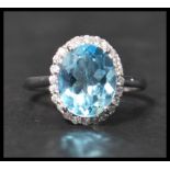 A 925 silver ring set with a large pale blue stone surrounded by a halo of CZ. Weight 3.5g. Size Q.