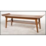 A Vintage retro teak wood mid century coffee table raised on shaped legs with under mag shelf, the