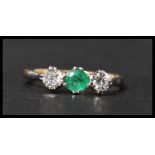 An 18ct gold and platinum three stone emerald and diamond ring having two 10pt diamonds with a