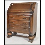 A 1930's Art Deco oak bureau desk raised on ball feet with a bank of drawers under a fall front