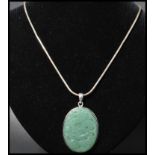 A 925 silver pendant necklace strung with a carved jade pendant with dragon decoration strung on a