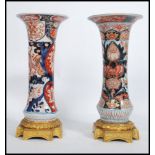 A near pair of late 19th Century Japanese Oriental Imari flared neck floral design vases raised on