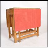 A retro 1950's red formica and beech wood drop leaf harvest table. The red formica top raised on