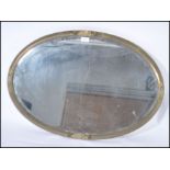 A late 19th century Arts and Crafts brass oval; framed wall mirror, the frame decorated in relief
