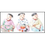 A group of three 19th century hand painted Oriental Chinese figurines of children modelled in seated