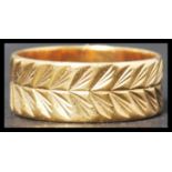 An 18ct gold band ring with a chased decorated finish weighing 5 g and measuring