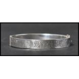 A silver hallmarked vintage ladies bangle bracelet having a half engraved foliate design with hidden