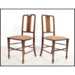 A pair of Edwardian mahogany inlaid bedroom chairs being raised on square tapered legs with