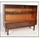 An retro 1970's teak wood glazed display cabinet having a pair of smoked glass sliding doors above a