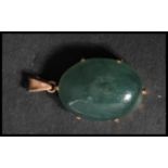 A vintage unmarked but tests as 9ct gold jade pendant. The large jade cabochon set to a pierced gold