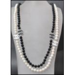 A long row of black and white freshwater pearls having enamel spacers with pendant attached