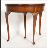 A 1930's good quality mahogany and walnut inlaid demi lune games - card table being raised on
