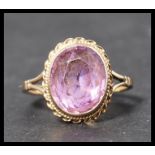 A hallmarked 9ct gold ring set with a faceted cut amethyst stone in a rope twist mount. Weighs 3.5