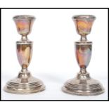 A silver hallmarked pair of candlesticks raised on terraced bases having trophy shaped stems and