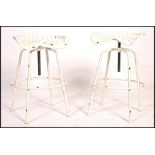A pair of contemporary retro Industrial stools with tractor seat tops on swivel columns and