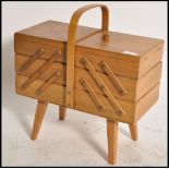 A vintage mid 20th century retro metamorphic sewing box with contents being raised on tapering legs