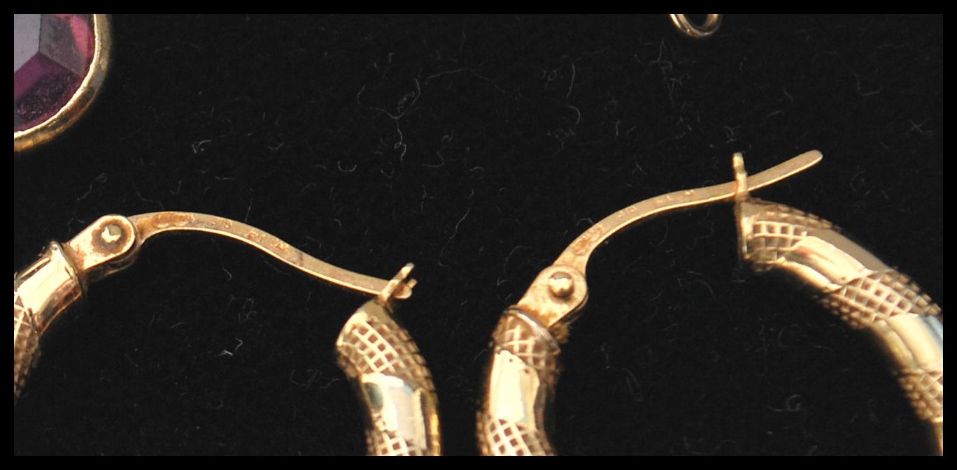 A group of 9ct gold earrings to include an engraved hoop pair, purple stone drop pair, star pair - Image 2 of 2