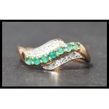 A hallmarked 9ct gold diamond and emerald crossover ring. Hallmarked Birmingham. Weight 2g. Size R
