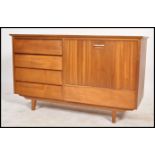 A 1970's retro teak wood Danish influence sideboard being raised on tapering legs with a bank of