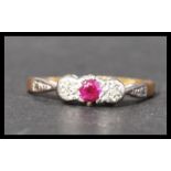 A 18ct gold platinum ruby and diamond three stone ring having stylised shoulders. Marked 18ct