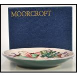 A Moorcroft ceramic pin tray coaster plate of circular form tube lined decorated with flowers in the