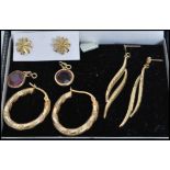 A group of 9ct gold earrings to include an engraved hoop pair, purple stone drop pair, star pair