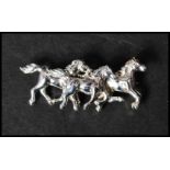 A 925 silver figural brooch in the form of galloping horses having a roller clip clasp. Measures 4.