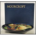 A Moorcroft ceramic pin tray coaster plate of circular form tube lined decorated with flowers in the