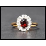 A hallmarked 18ct gold diamond and garnet stone cluster ring having a central faceted stone with a